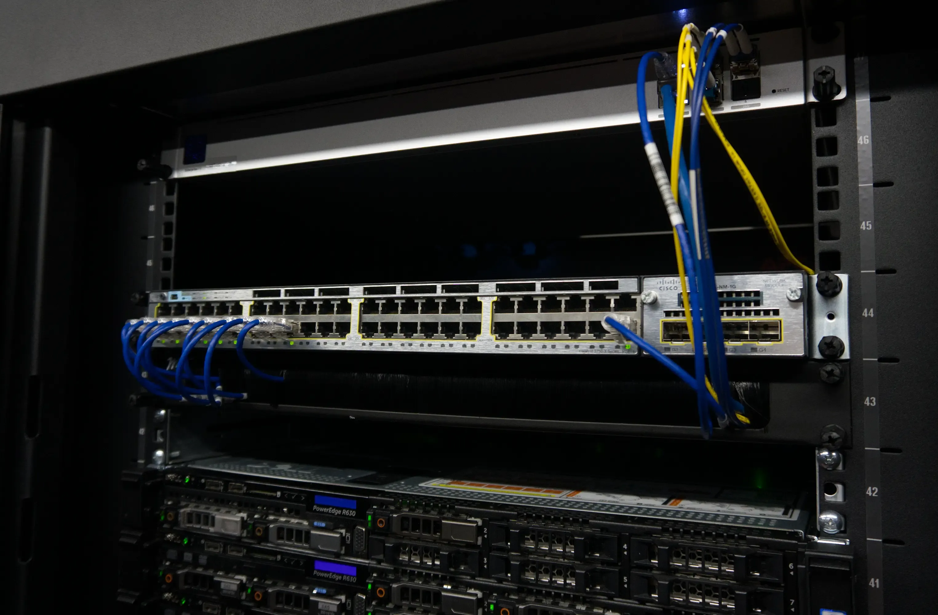 Front view of a 48 port Cisco network switch with 10 of its ethernet ports populated within a datacenter rack.